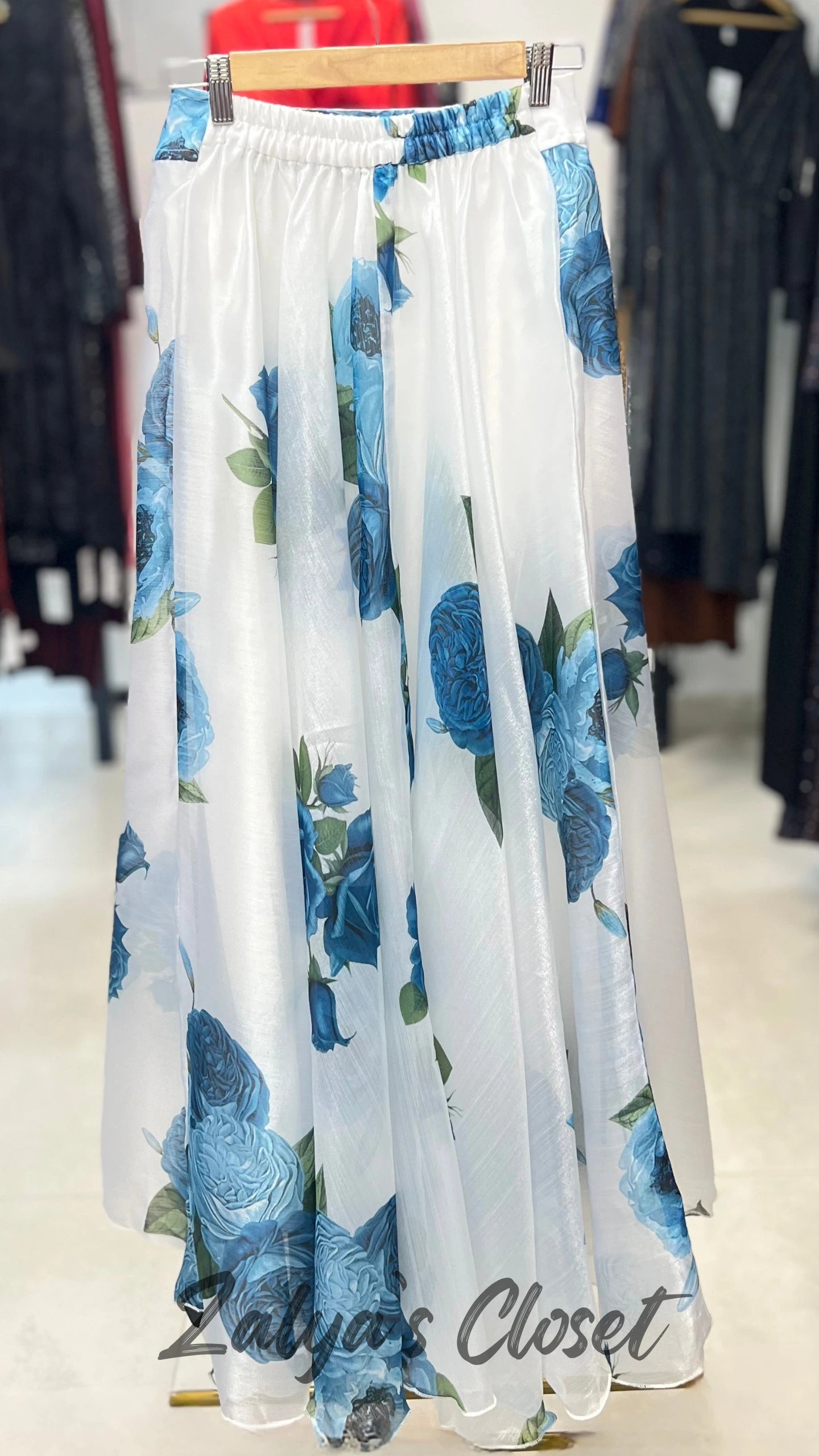 White skirt with blue floral pattern on a hanger in a store setting